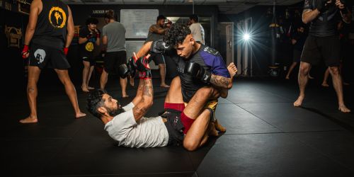 Two men engaged in a grappling exercise during a martial arts training session