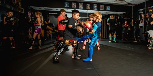 A group of young children practicing martial arts in a gym