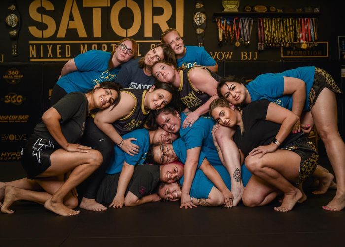 A group of women from Satori Mixed Martial Arts posing together in a playful