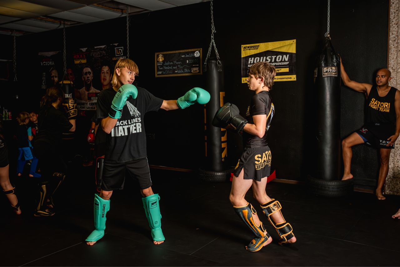 Two boys practicing kickboxing in a gym